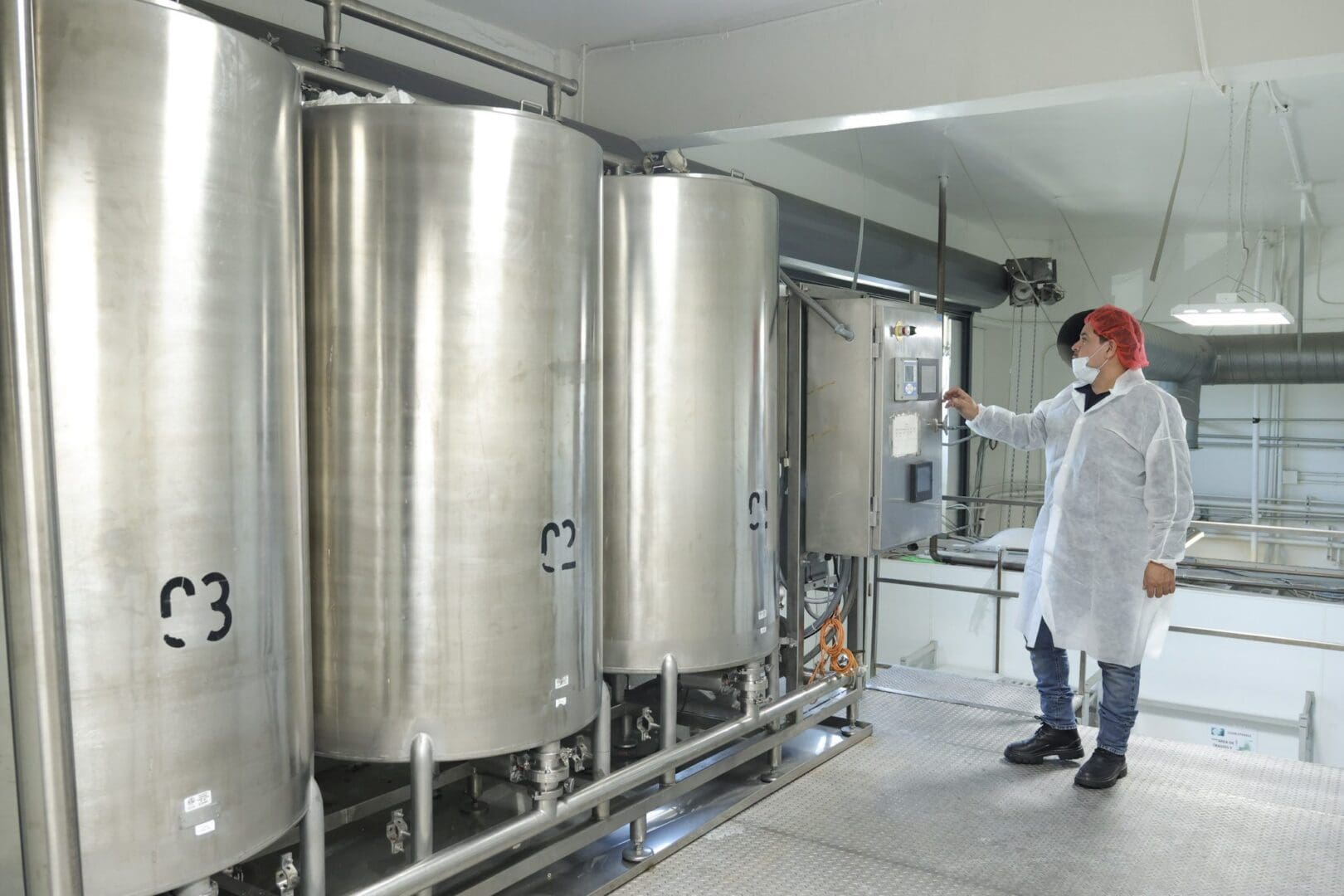 Worker inspecting stainless steel processing tanks